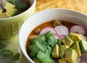 This easy red posole for the pressure cooker or crock pot is topped with cilantro, avocado and sliced radishes.