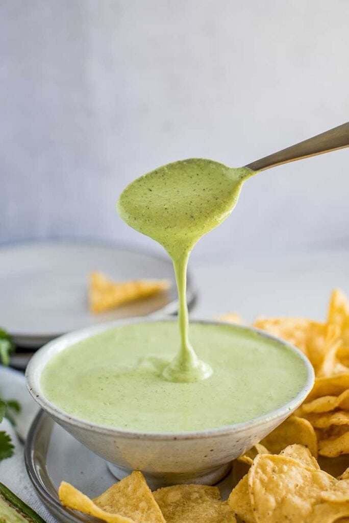 Creamy Jalapeno Sauce in a bowl with spoon surrounded by chips
