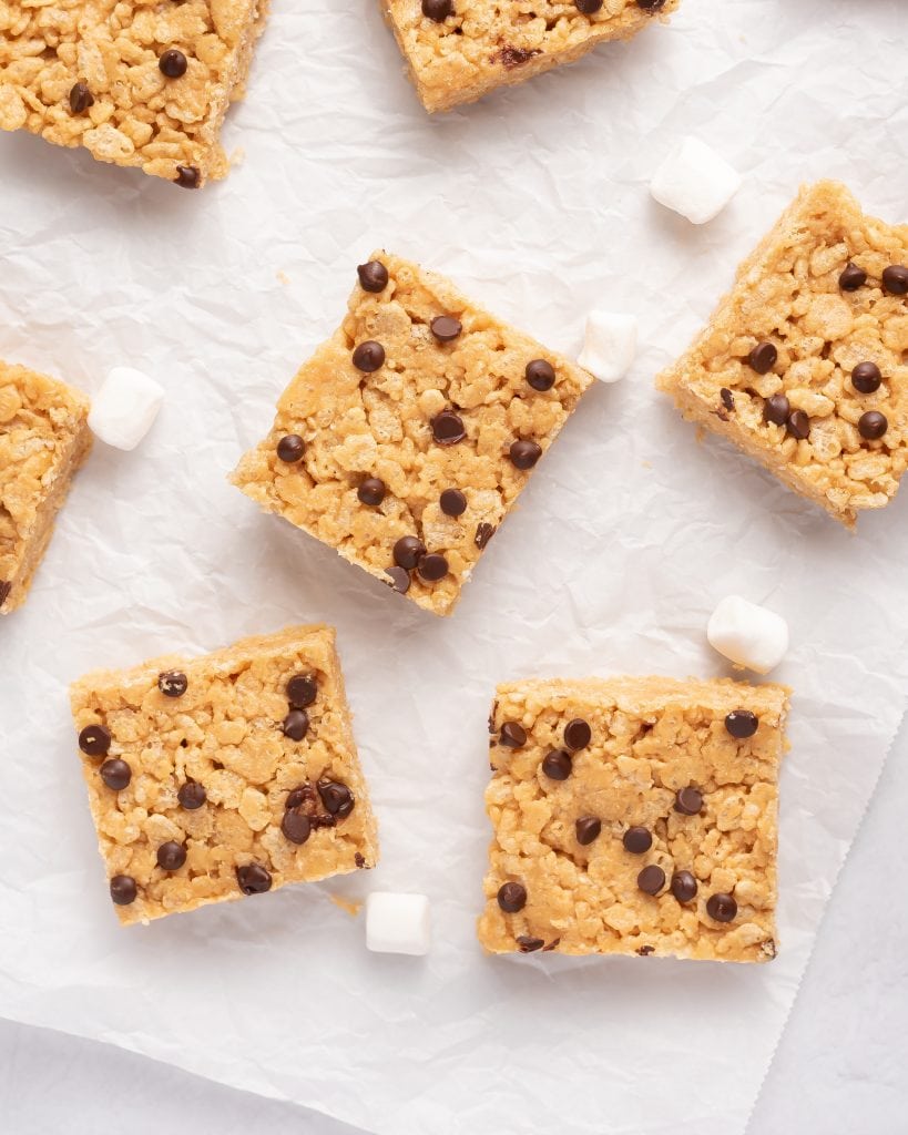 peanut butter rice krispie treats with chocoalte chips on a piece of parchment paper