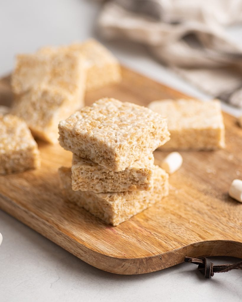 Vegan rice crispy treats in a stack on a wooden cutting board