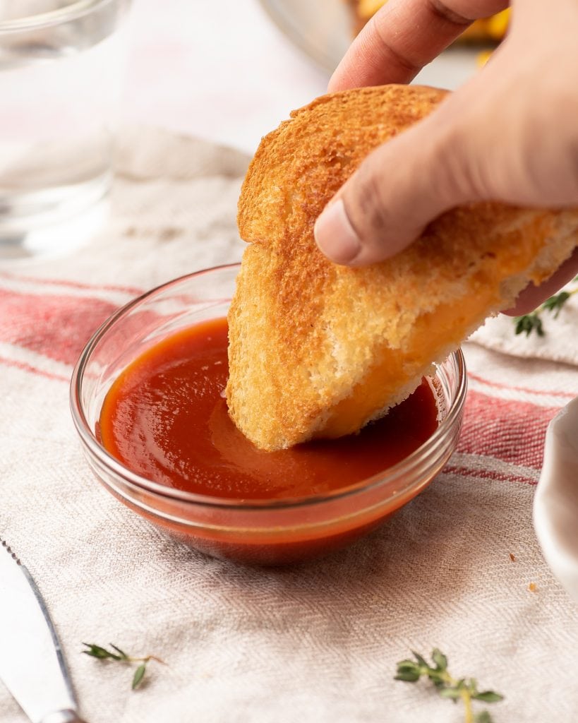 dipping a cheese sandwich in a bowl of ketchup