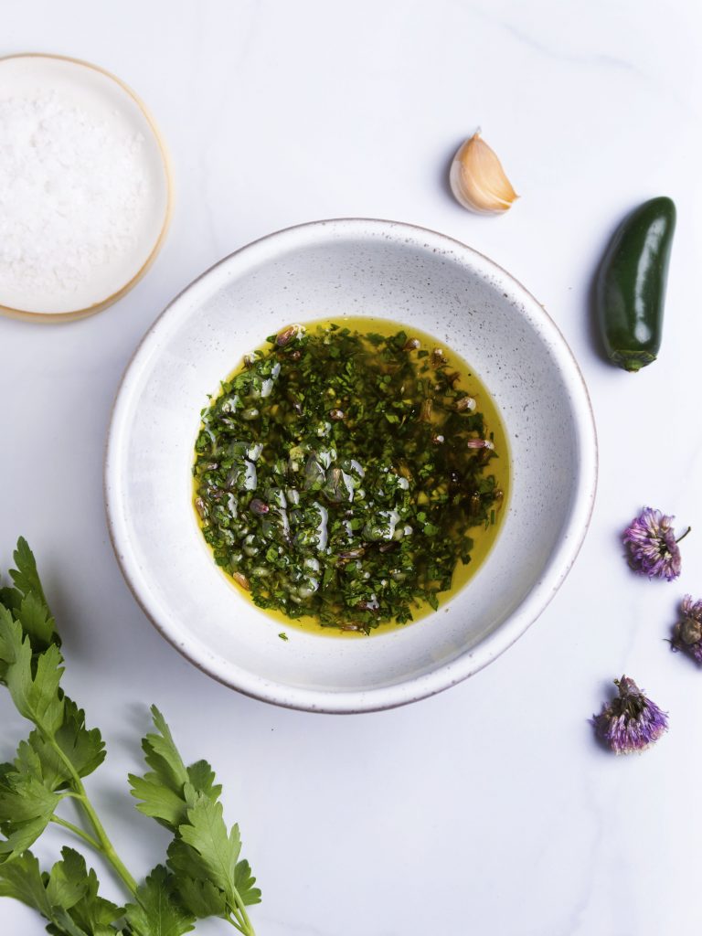 herb oil in a white bowl made with fresh herbs, pepper and garlic