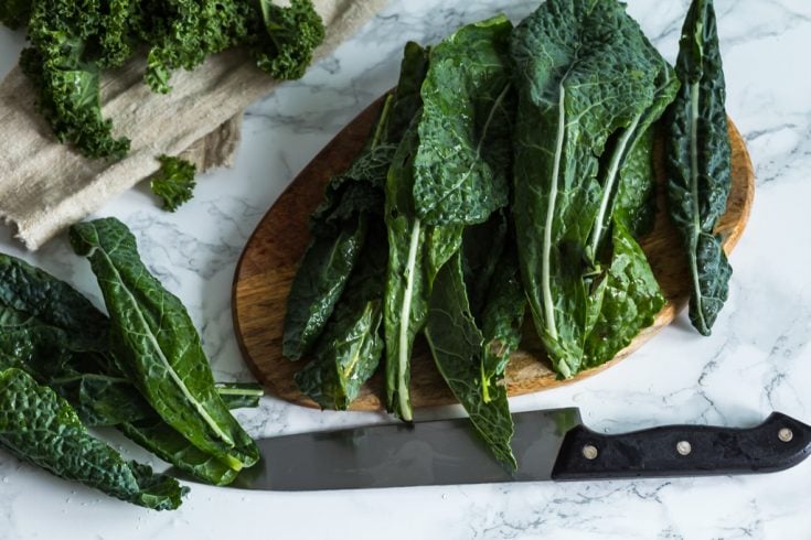 whole kale leaves on a wooden cutting board