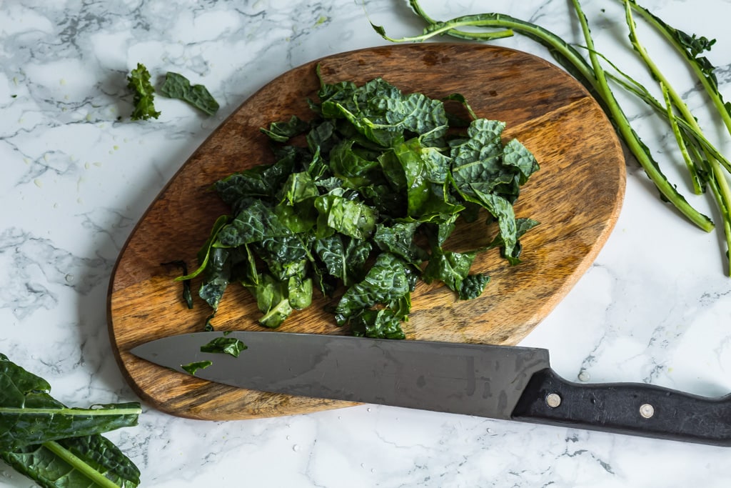 cut kale leaves on a wooden cutting board