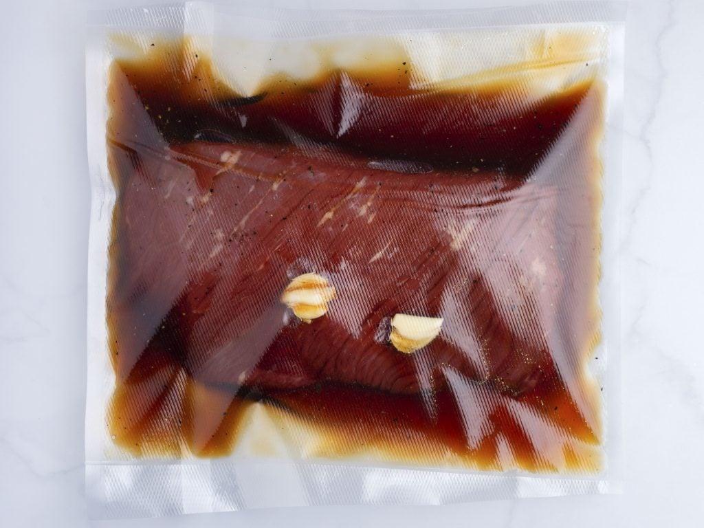 flank steak and teriyaki sauce with crushed garlic in a plastic bag