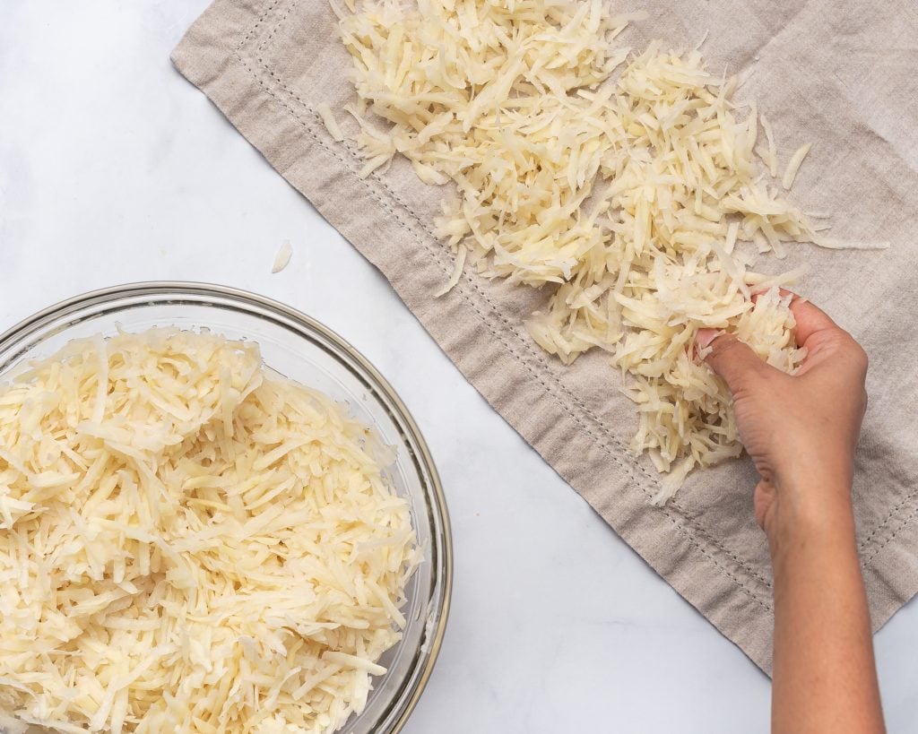 drying grated potatoes on a grey dish towel